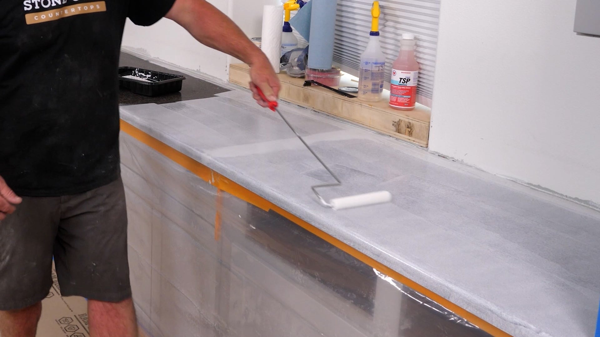 A man painting primer onto a countertop