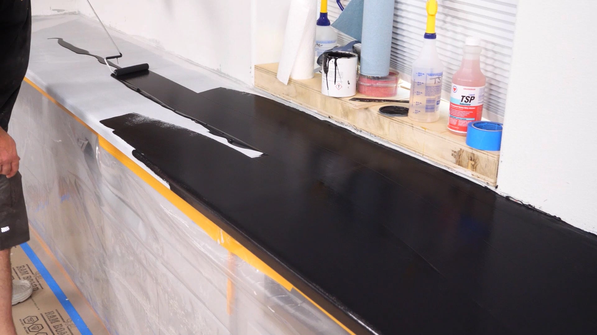 A man painting the primed countertop black