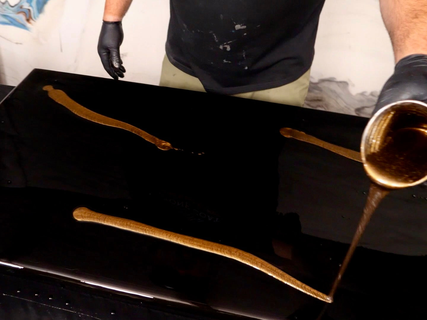 Man pouring gold epoxy onto a black countertop