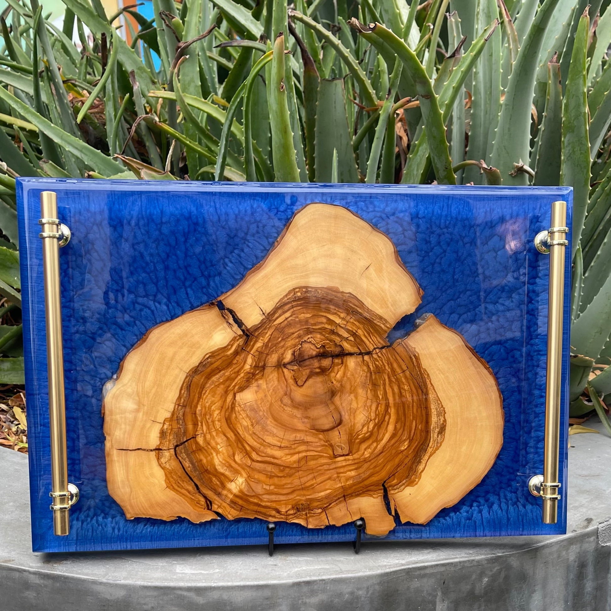 A custom epoxy serving tray that is blue epoxy with a piece of treen trunk in the middle