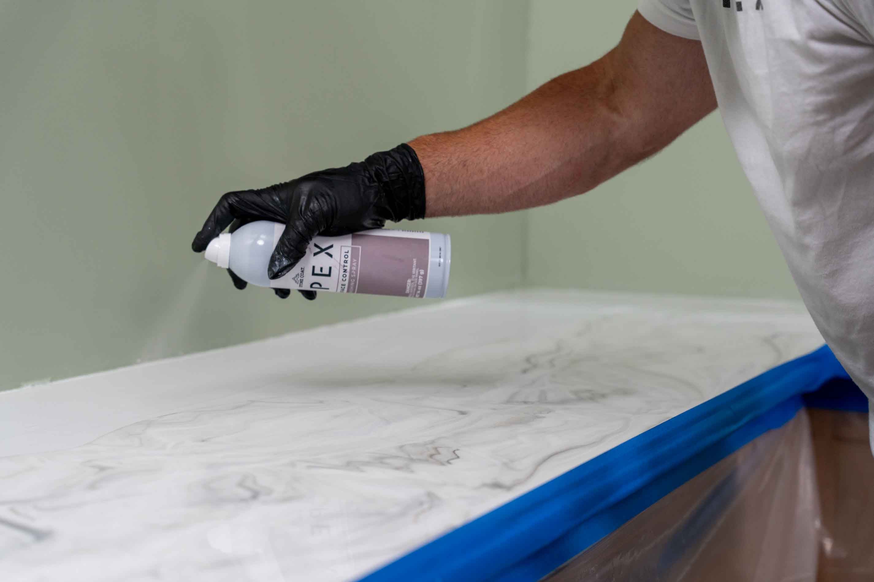 apex surface control spray being applied to a white marble countertop