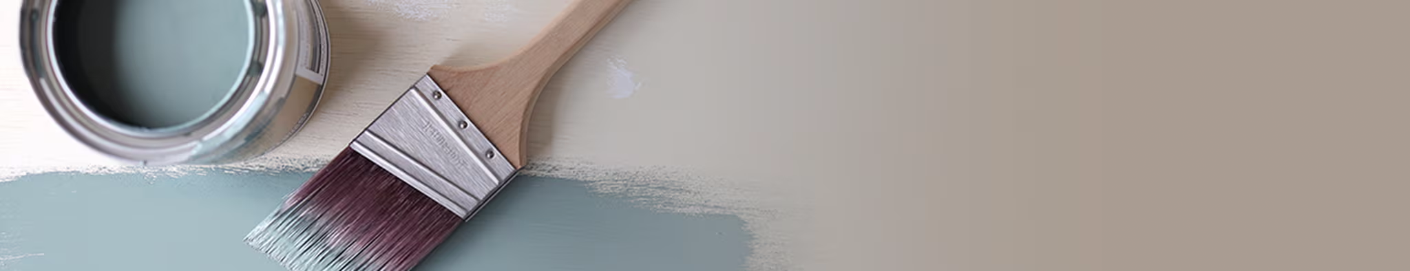 Image of a paintbrush next to an open can of paint