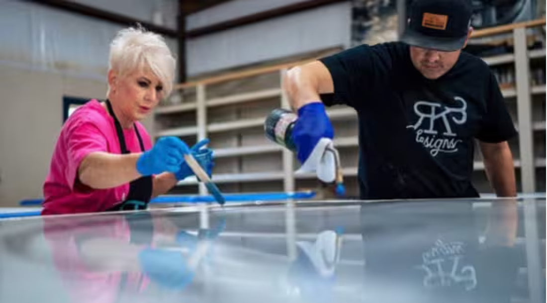 Man and women pouring and heating the puddles out of an epoxy table