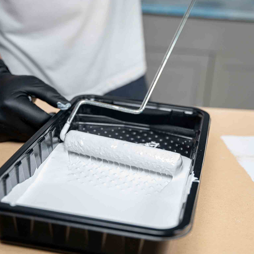 Paint roller being used to prime a counter with white poly fuse primer.