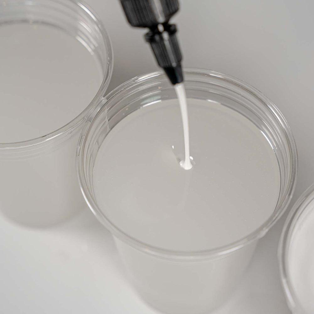APEX Poly White Countertop Dye being dripped from a dropper into a clear container on a white background
