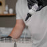 Person pouring APEX Poly White liquid dye from a bottle labeled into a clear container.