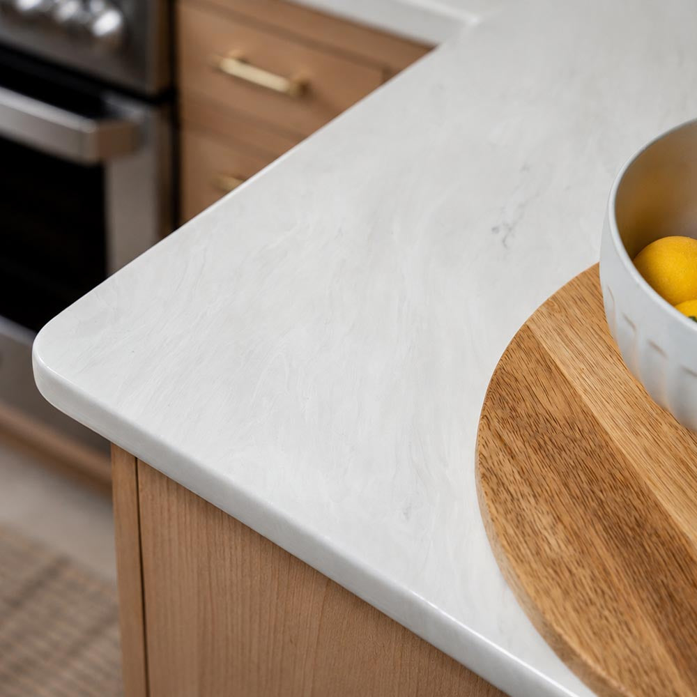Close-up of a Carrara kitchen counter with a cutting board and bowl.