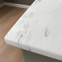 Close-up of a carrara marble countertop with a wooden floor in the background