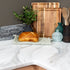 Wooden cutting boards, loaf of bread, and kitchen utensils on an APEX marble countertop.