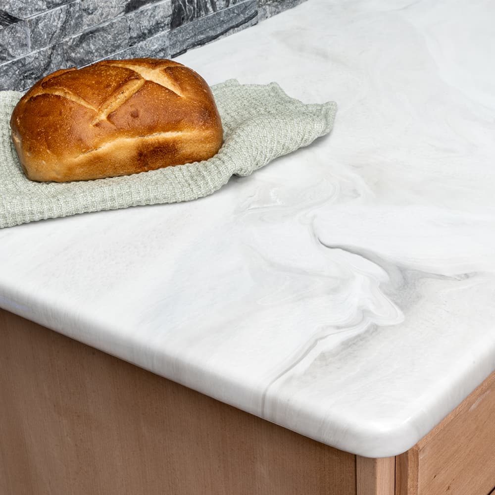 Carrara marble kitchen countertop with loaf of bread and kitchen towel.