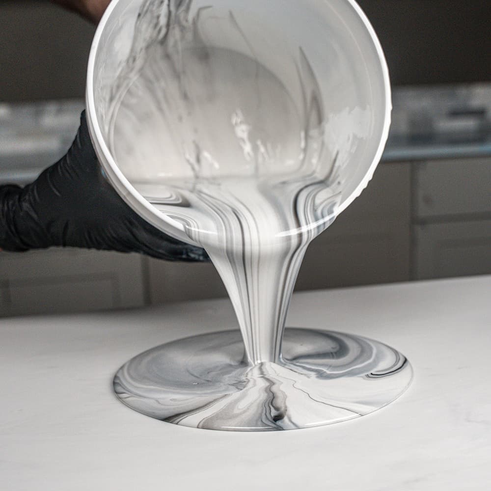 Marbled white and gray APEX being poured from a container onto a surface.