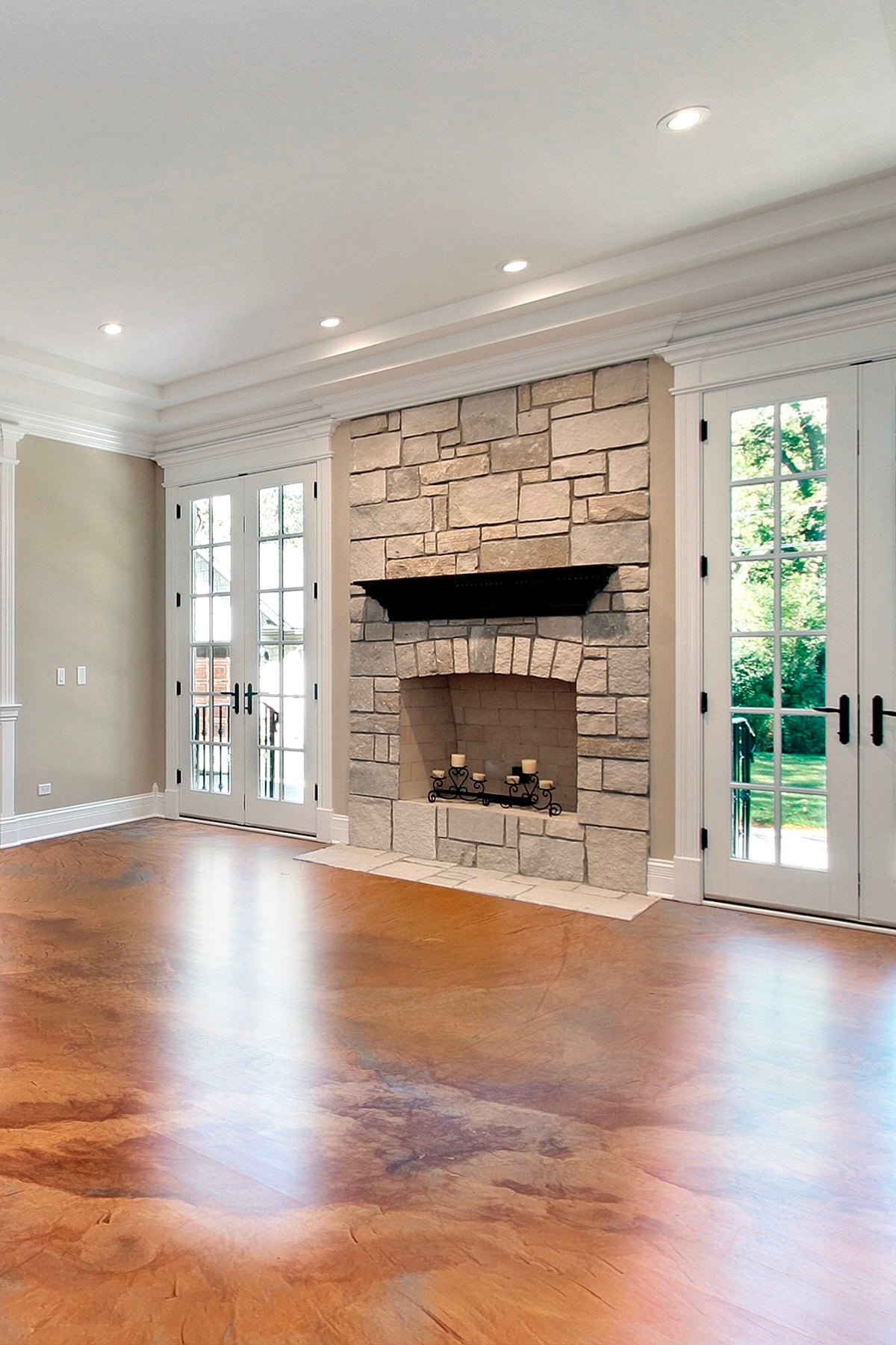 Living room with stone fireplace, metallic marlbe epoxy flooring, and large windows