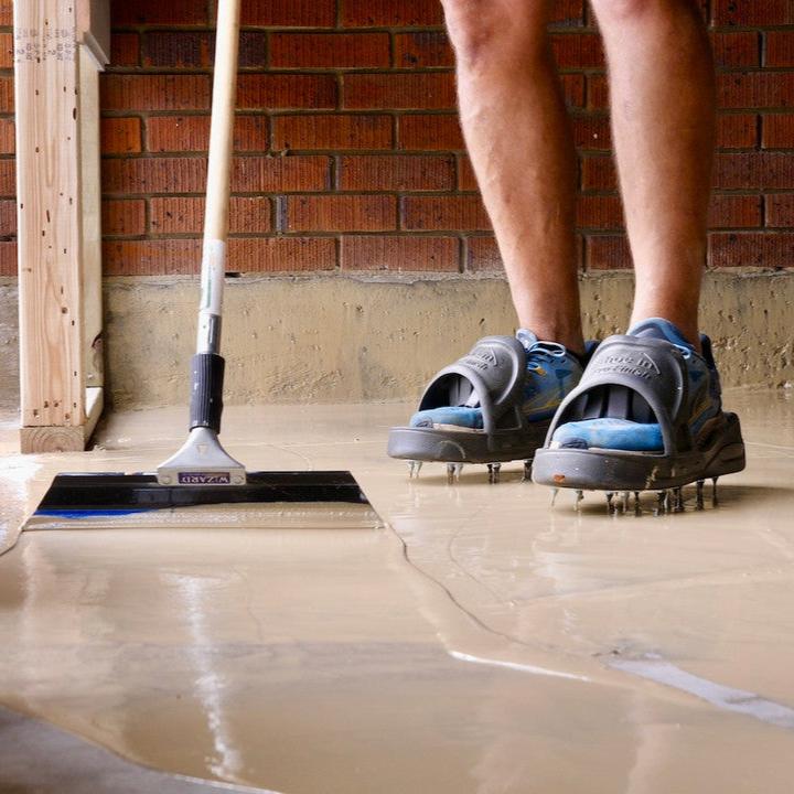 Spreading tan floor primer on concrete floors