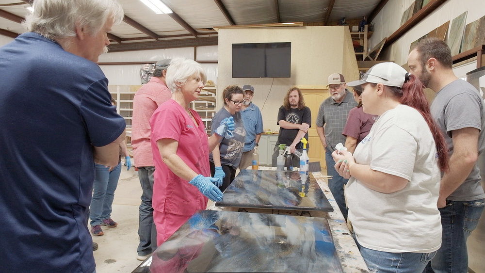 People in an epoxy class looking over finished epoxy paintings