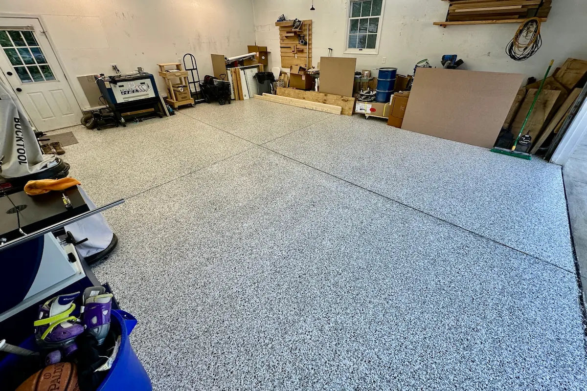 Garage with a newly installed epoxy floor, tools, and materials scattered around.