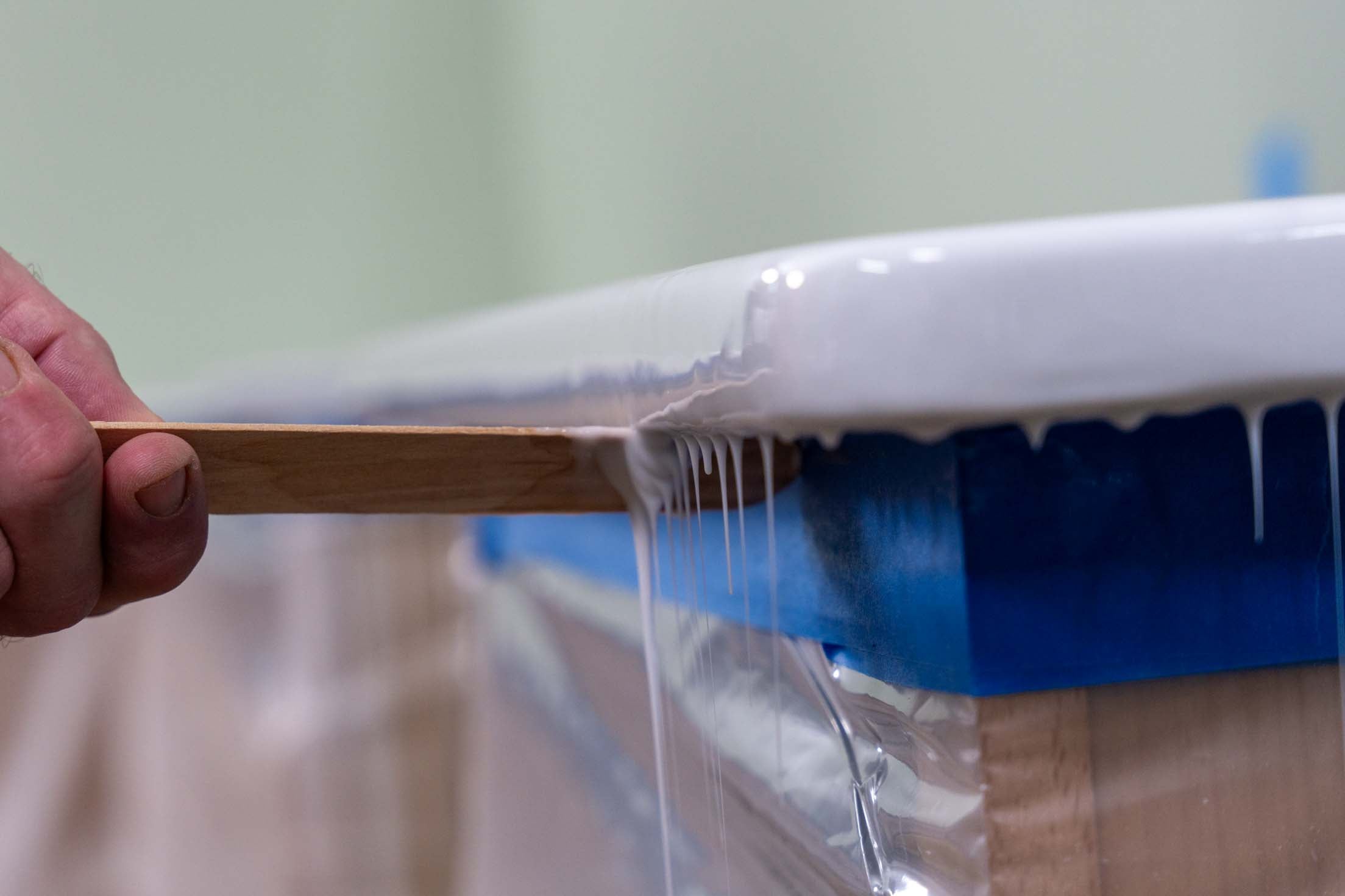 using a paint stick to remove polyaspartic drips from underneath a kitchen countertop