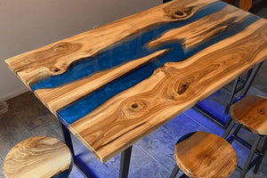 Wooden table with blue resin inlay and stools around it.